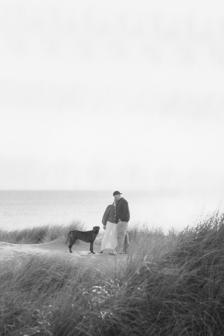 Sort-hvidt hundefotografi fra Hvide Sande med par og hund i klitterne.