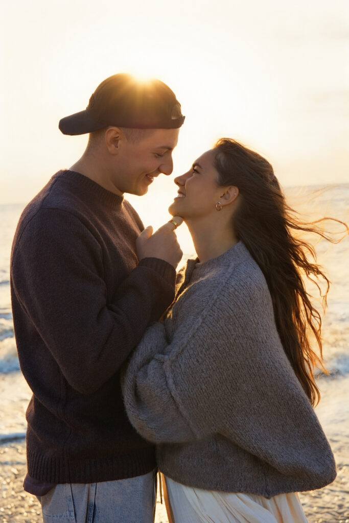 Couple embracing on Henne beach at sunset, knit sweaters, warm backlight, windblown hair, Hundefotografie.