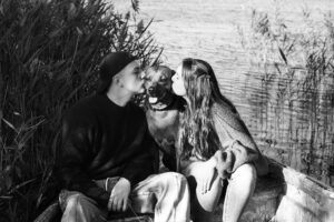 Hundefotografie in Blåvand: Schwarz-Weiß, Paar küsst Hund im Boot